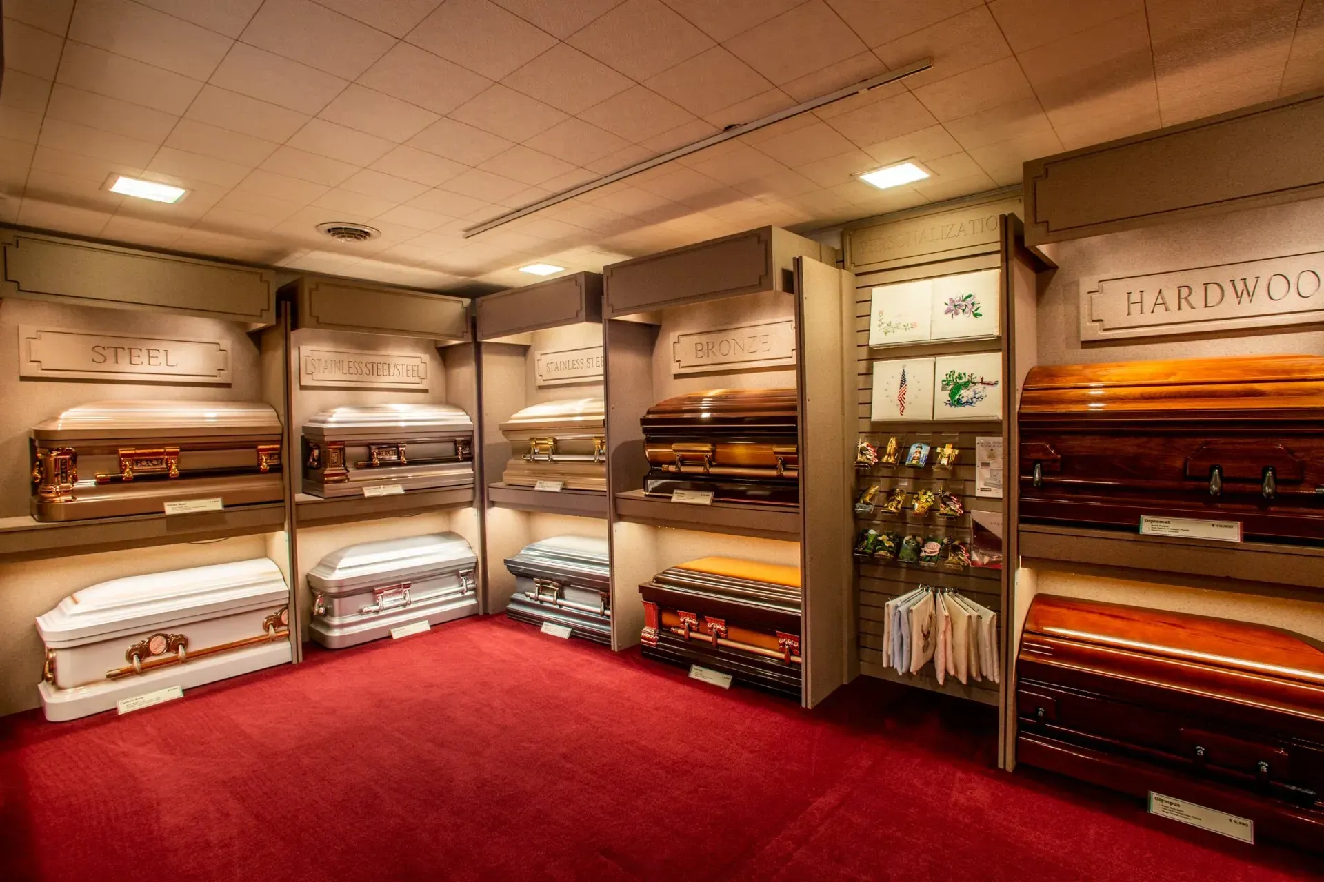 Showroom of carpet and rug samples displayed on shelves, with red carpet flooring and warm lighting