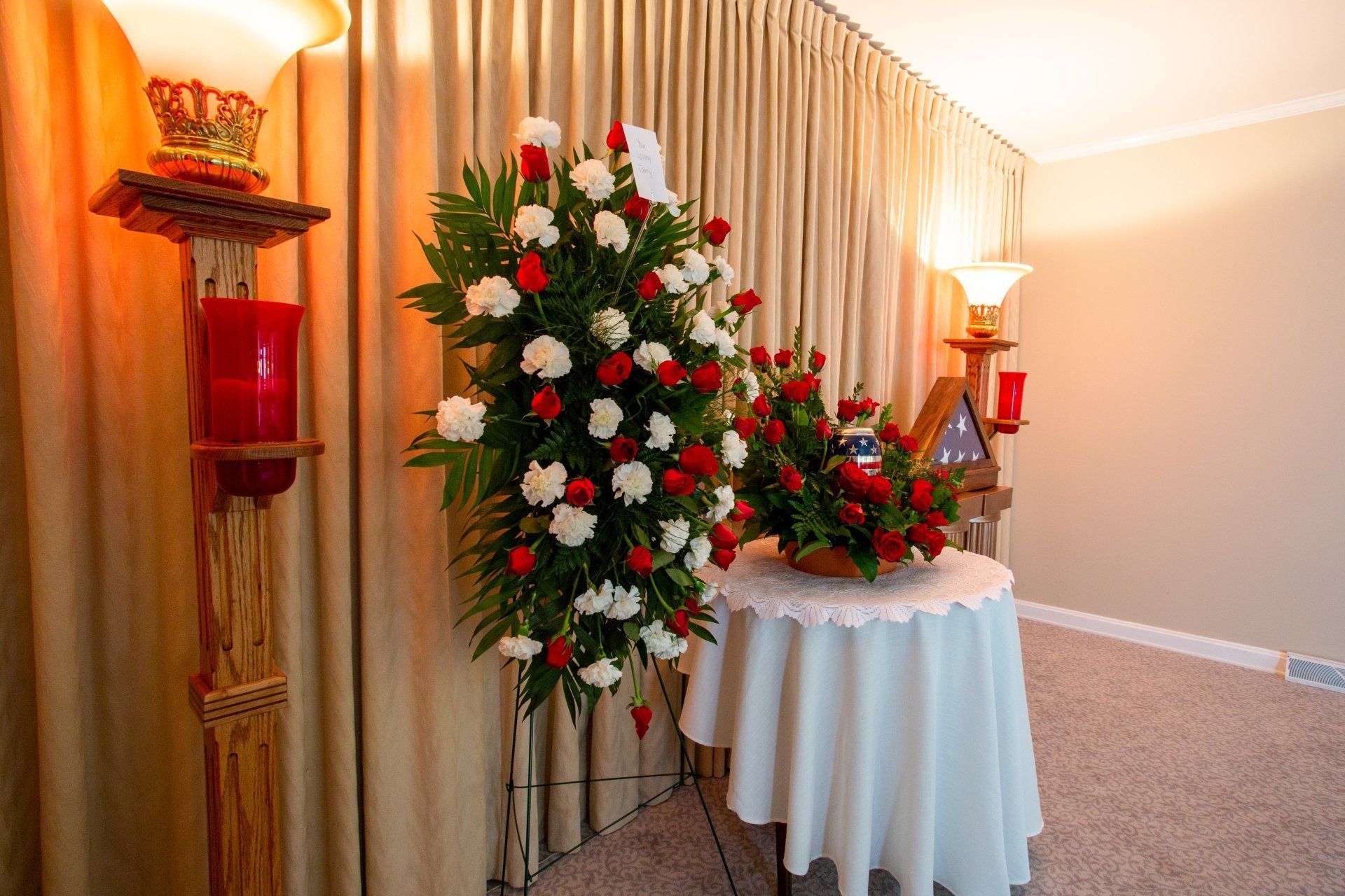 Christmas tree and floral arrangement beside a white-draped table in a decorated indoor corner
