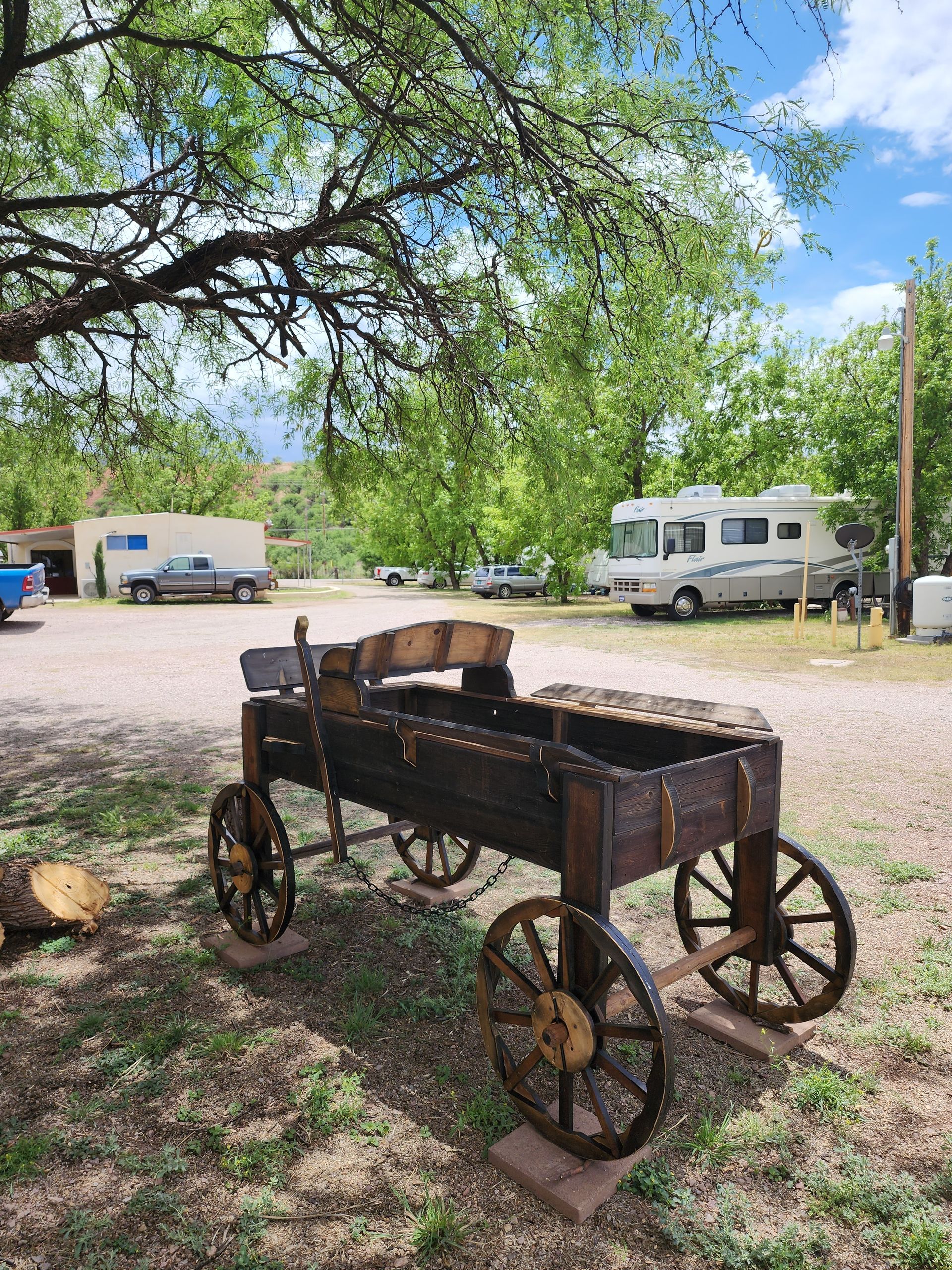 A wooden wagon is parked in a parking lot next to a tree.