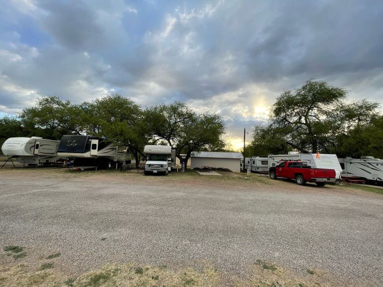 A lot of rvs are parked in a gravel lot.