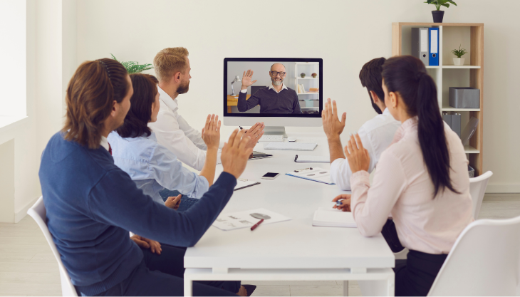 Team of onsite workers greet their colleague remotely, showing the benefits of a hybrid workplace model implemented successfully