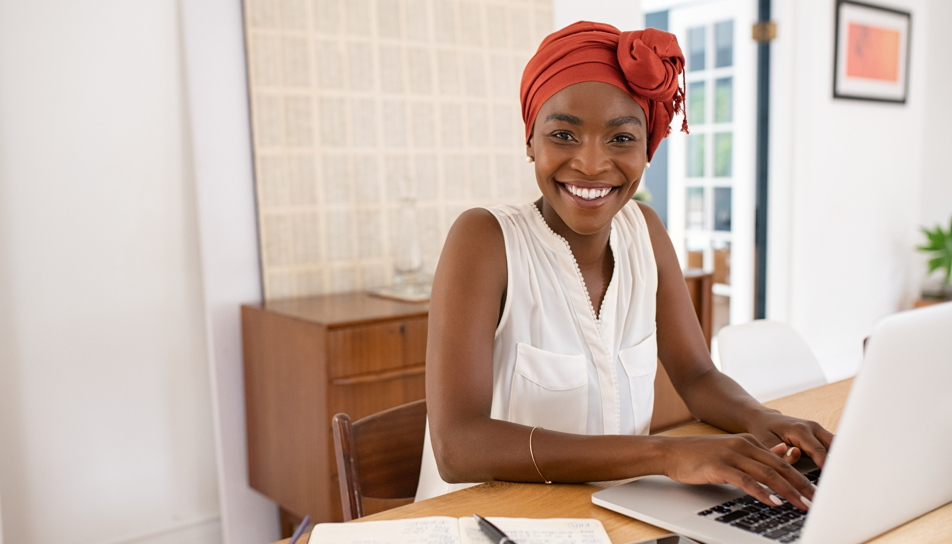 A woman smiles at the camera as she is happily working from home following mental health tips