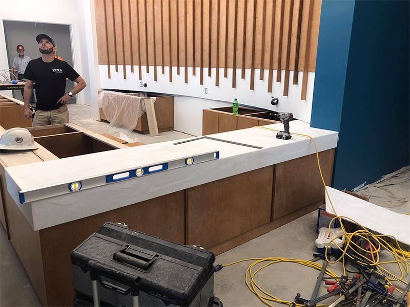 A man is standing in front of a counter in a kitchen under construction.