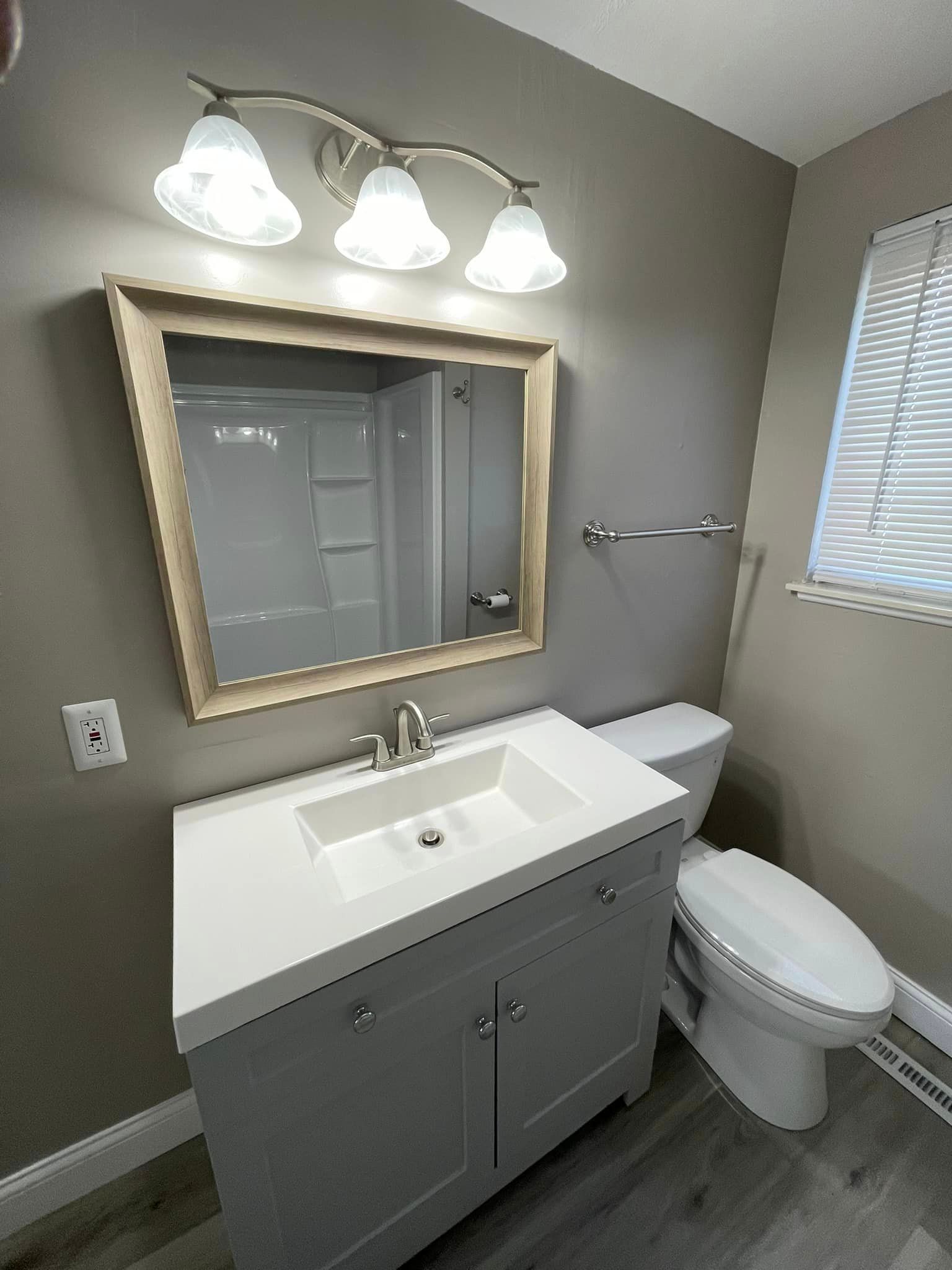 A bathroom with a sink , toilet and mirror.