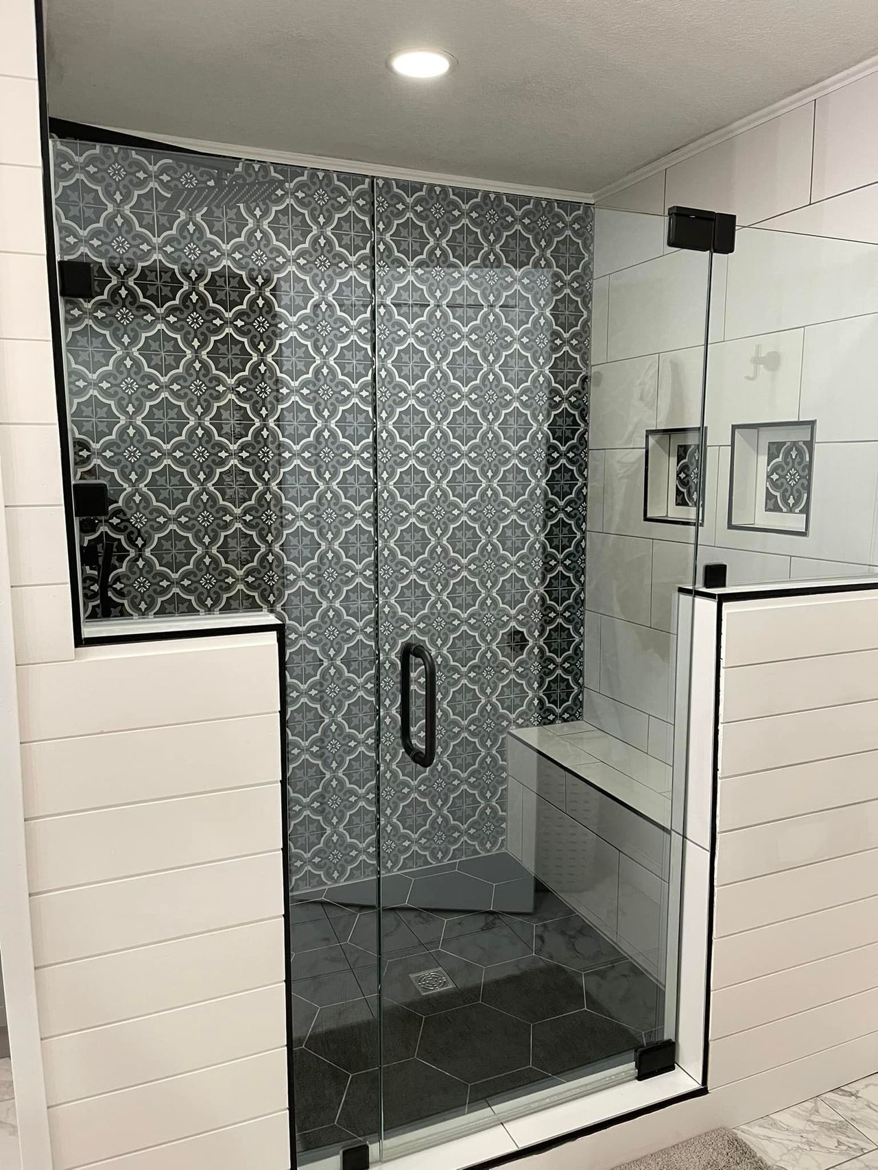 A bathroom with a glass shower door and a bench.