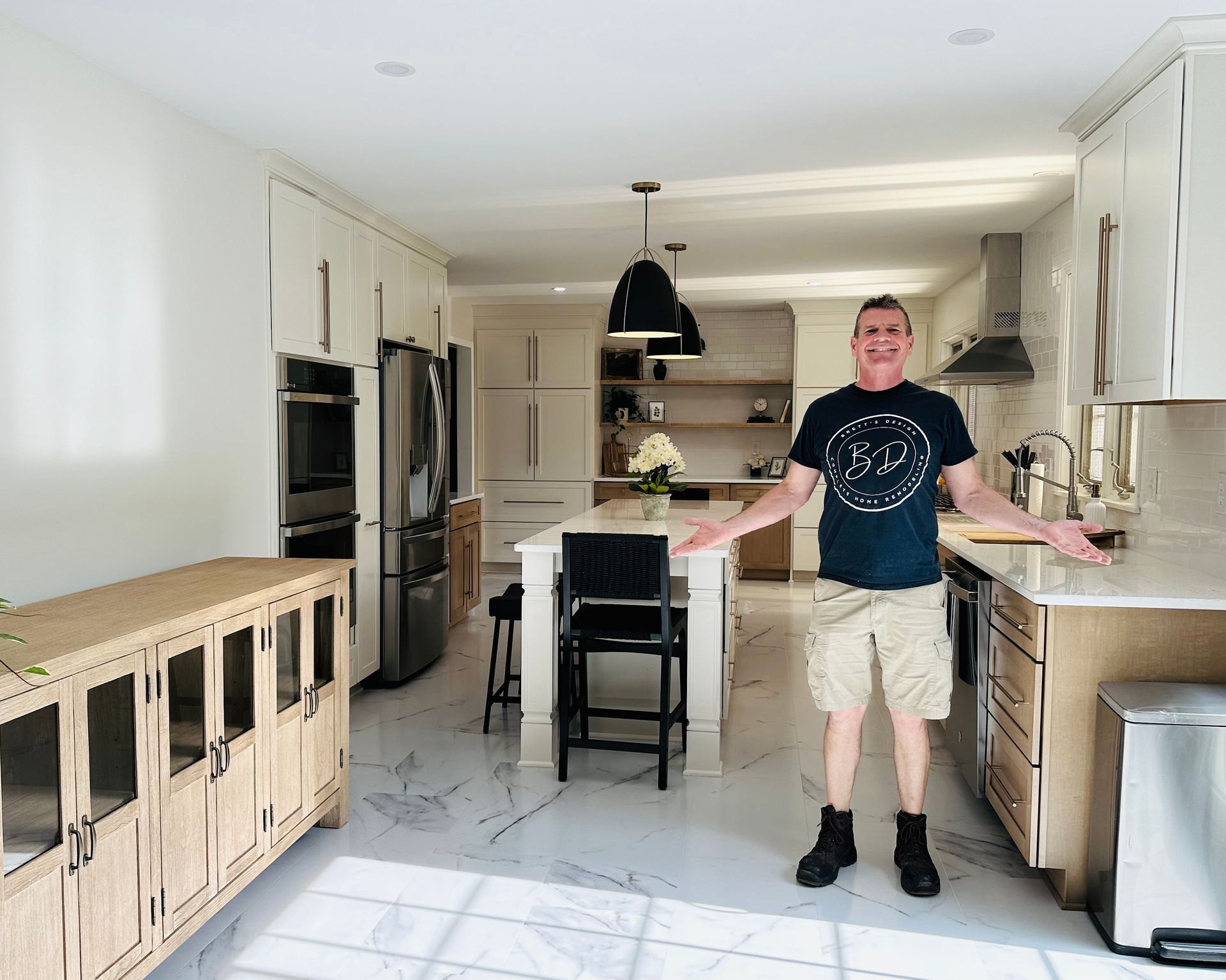 A man is standing in a kitchen with his arms outstretched