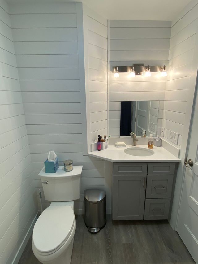 A bathroom with a toilet , sink and mirror.