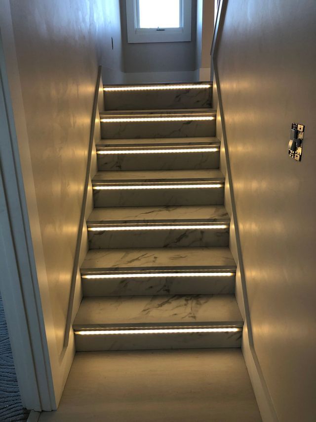 A set of stairs with lights on the steps in a hallway.