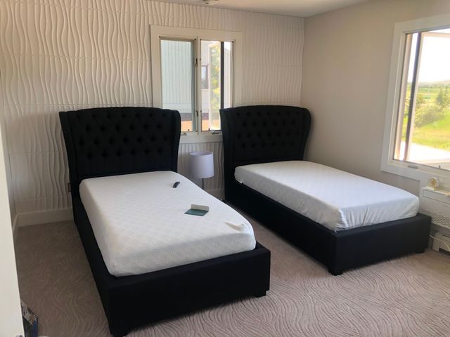 A bedroom with two twin beds and a window.