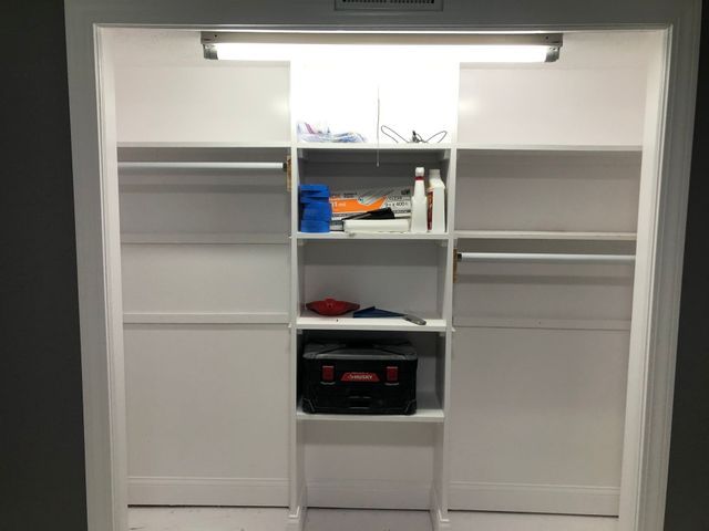 A closet with shelves and a box on the bottom shelf