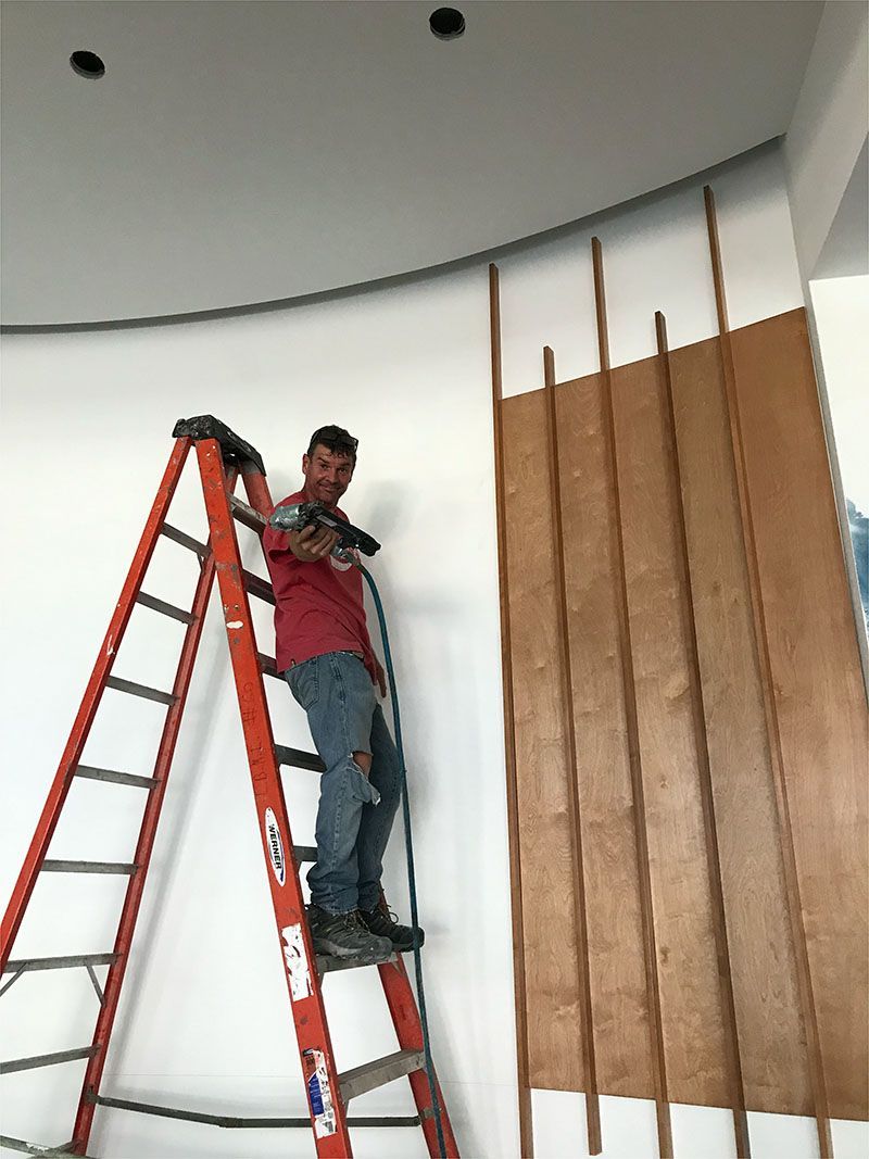 A man is standing on a ladder working on a wall.