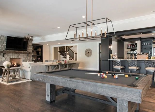 A pool table is in the middle of a living room.