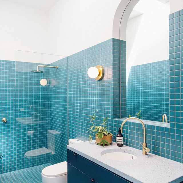 A bathroom with blue tiles and a sink and toilet