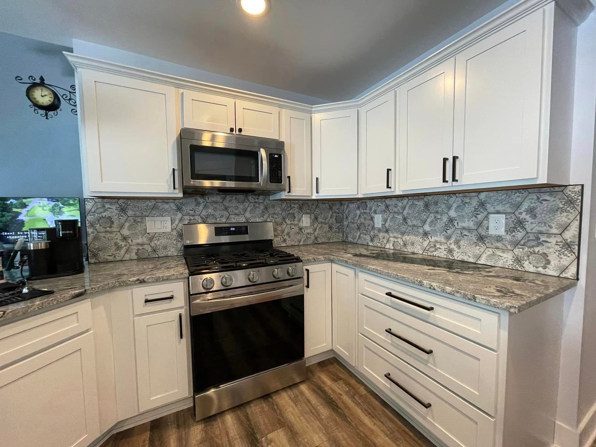 A kitchen with white cabinets , stainless steel appliances and granite counter tops.