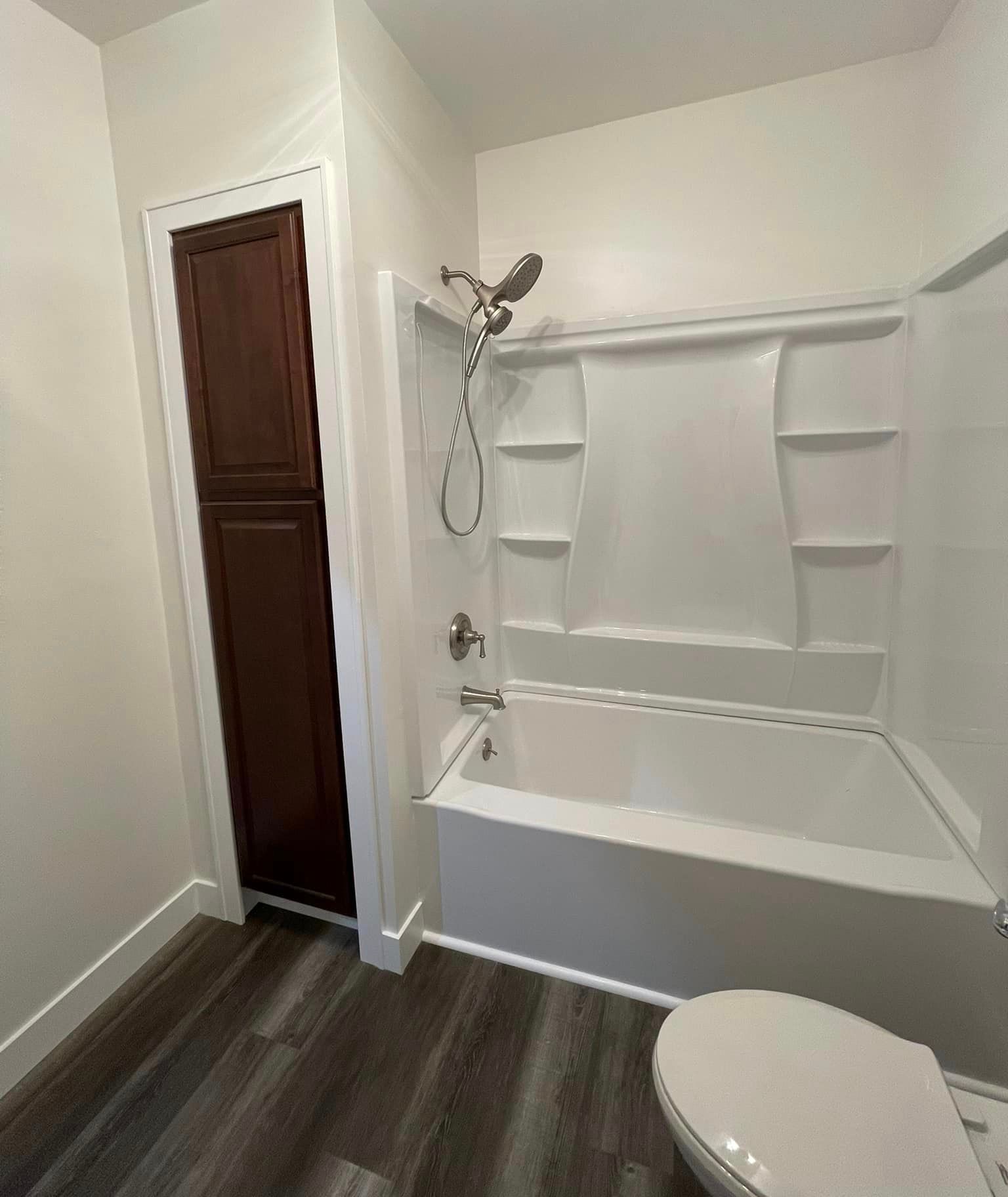 A bathroom with a tub , toilet and shower.