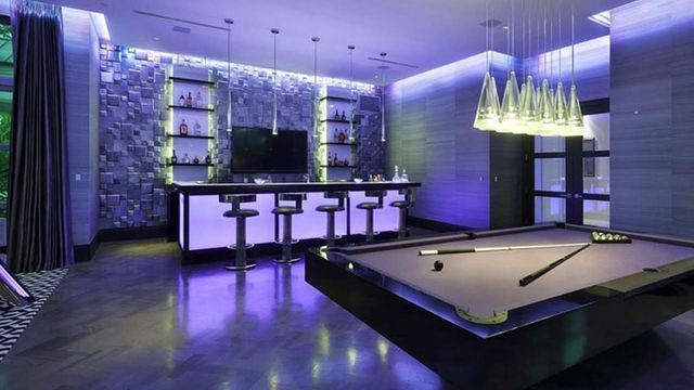 A pool table in a room with purple lights