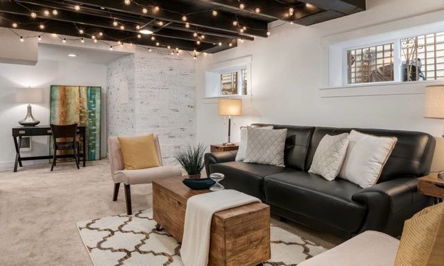 A living room with a couch , chair , coffee table and string lights.