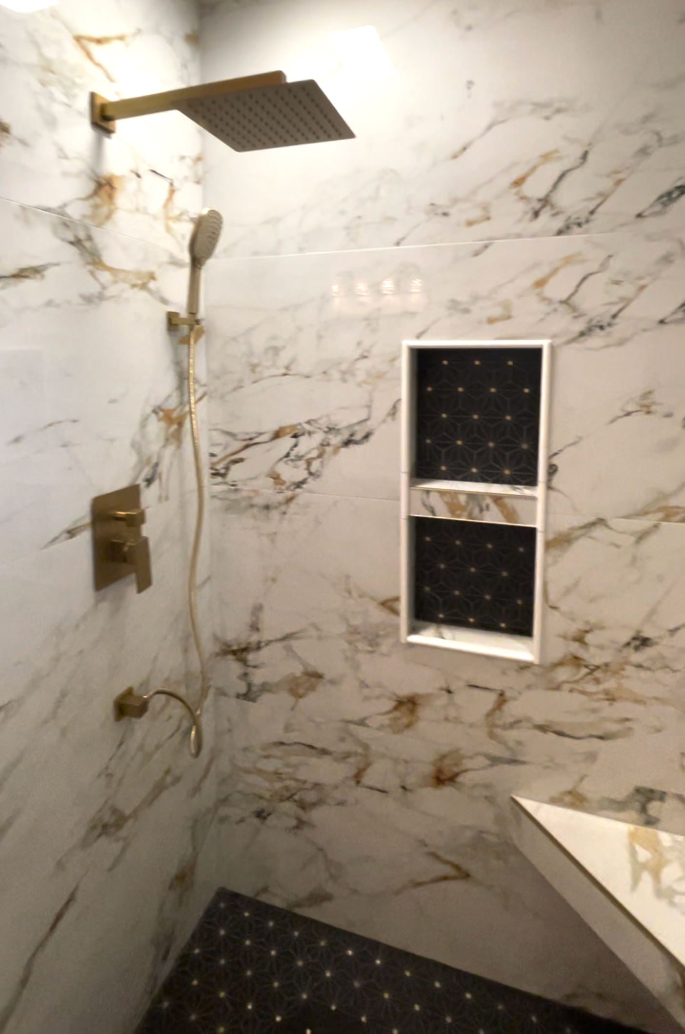 A bathroom with marble walls and a shower head