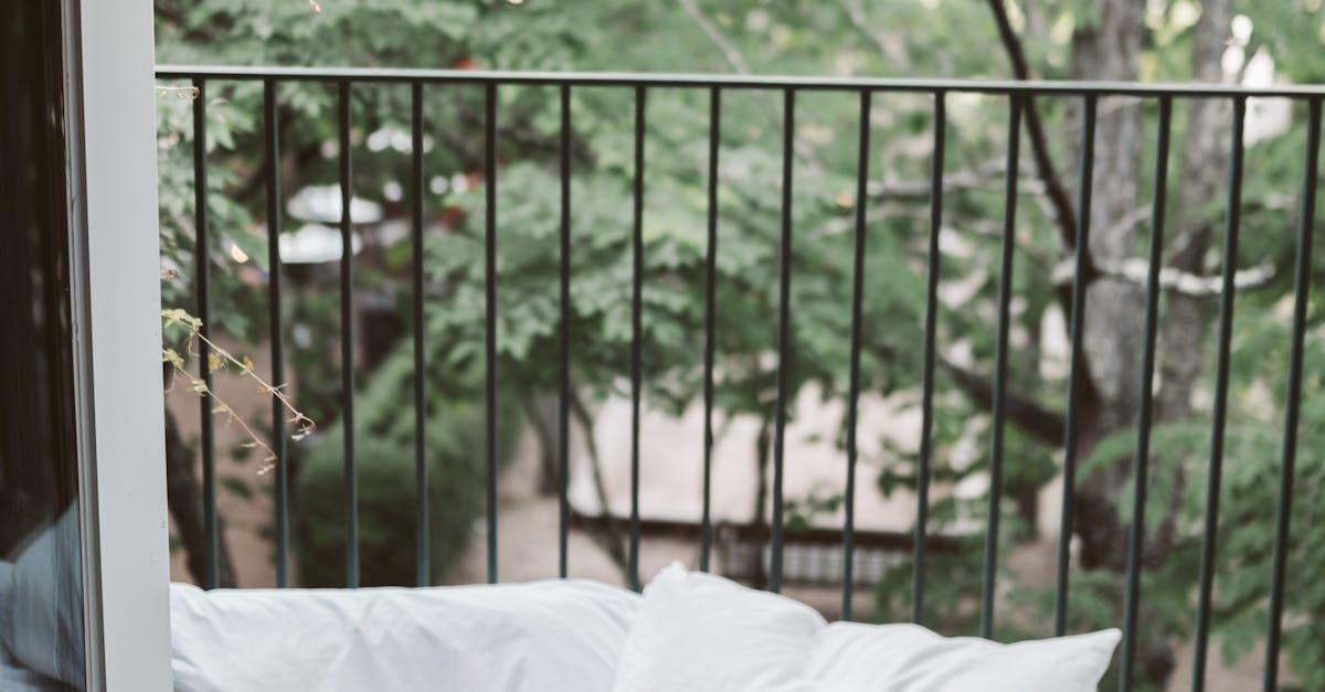 A person is sitting on a balcony with a view of trees.