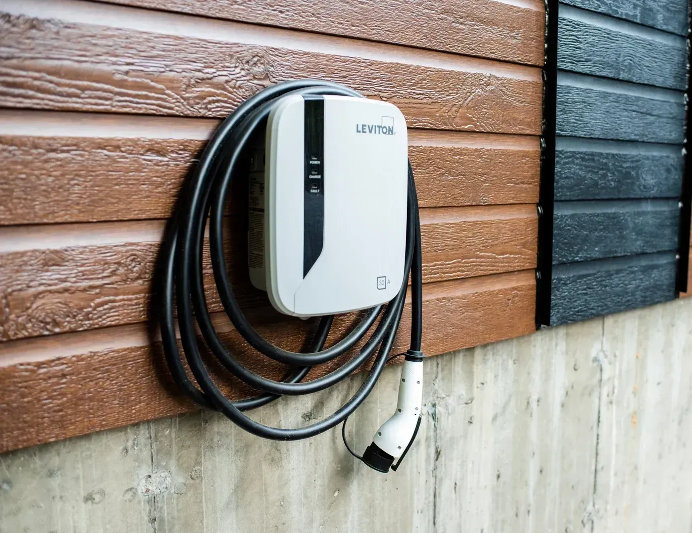An electric car charger is attached to the side of a building.