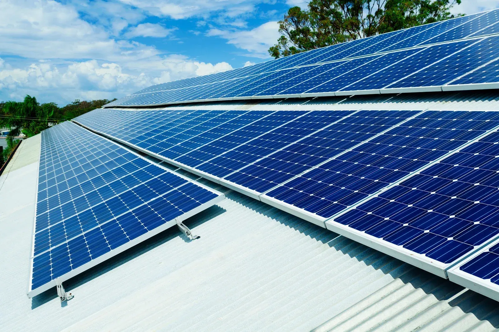 There are many solar panels on the roof of a building.