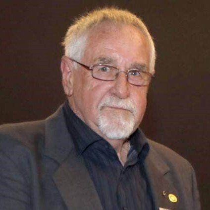 A man with glasses and a beard is wearing a suit.