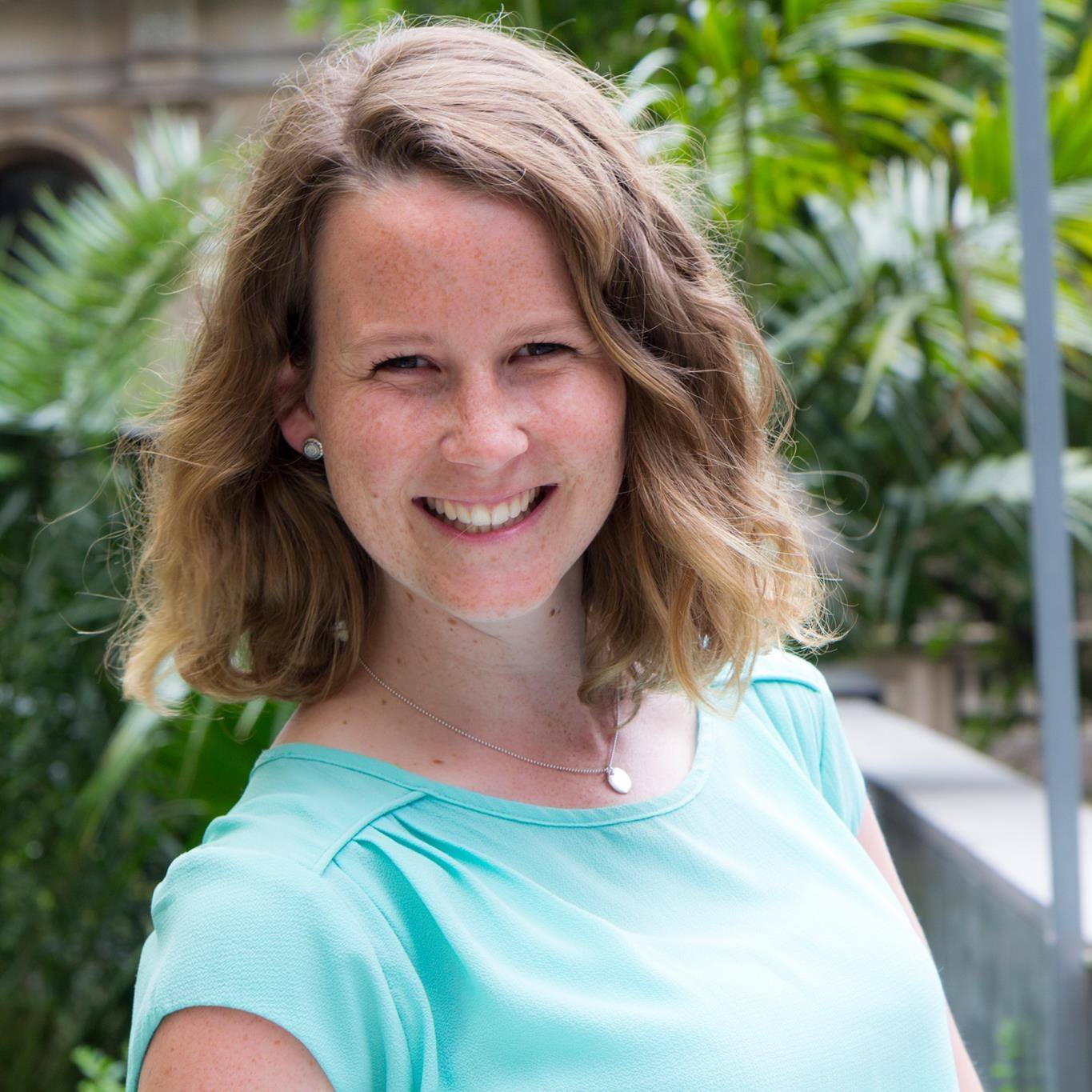 A woman in a blue shirt is smiling for the camera.