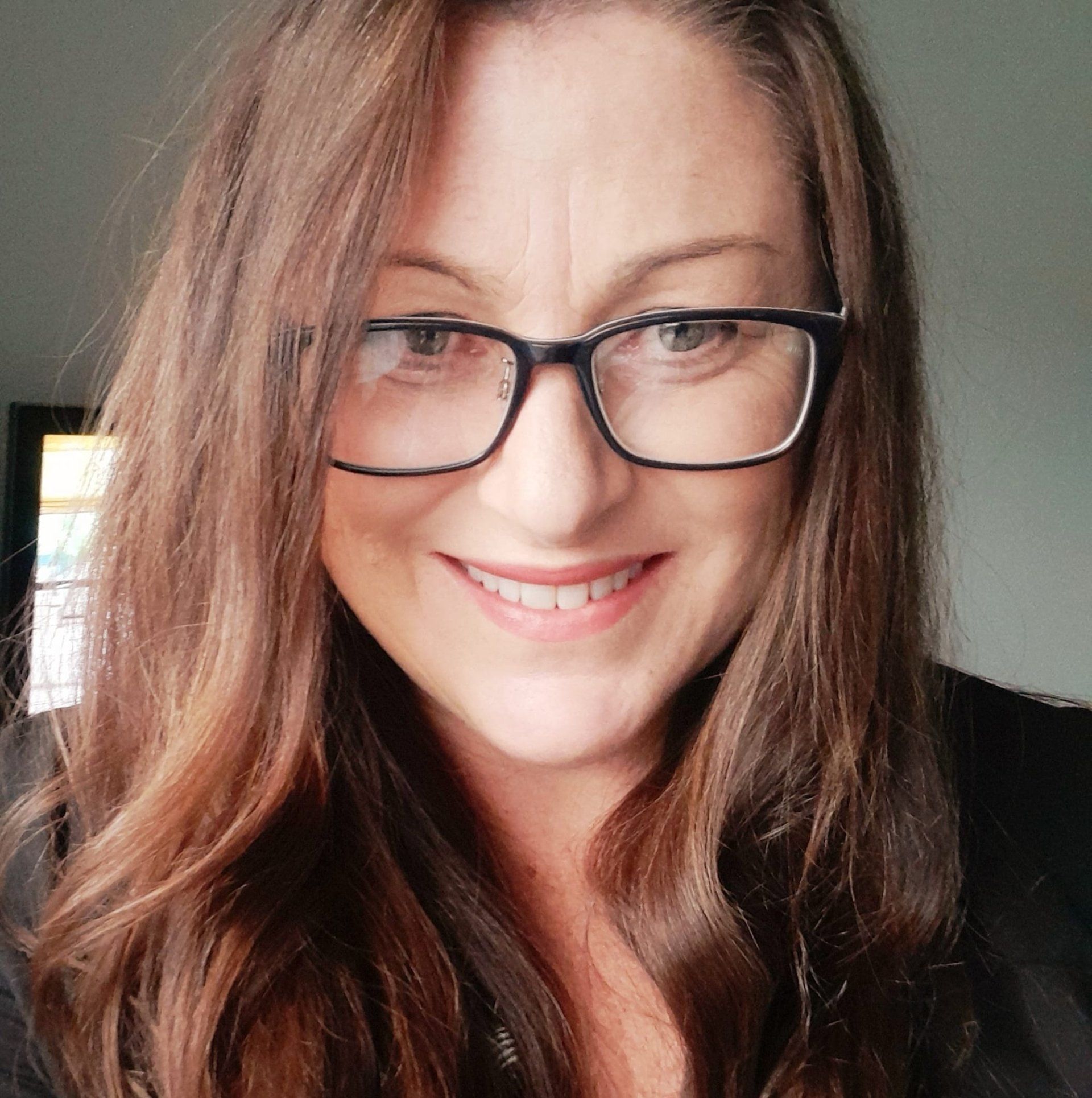 A woman wearing glasses is smiling for the camera.