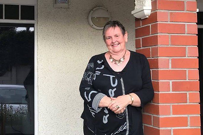 A woman is standing in front of a brick wall.