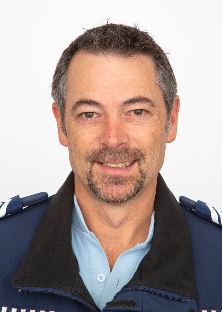 A man with a beard is wearing a blue jacket and smiling for the camera.