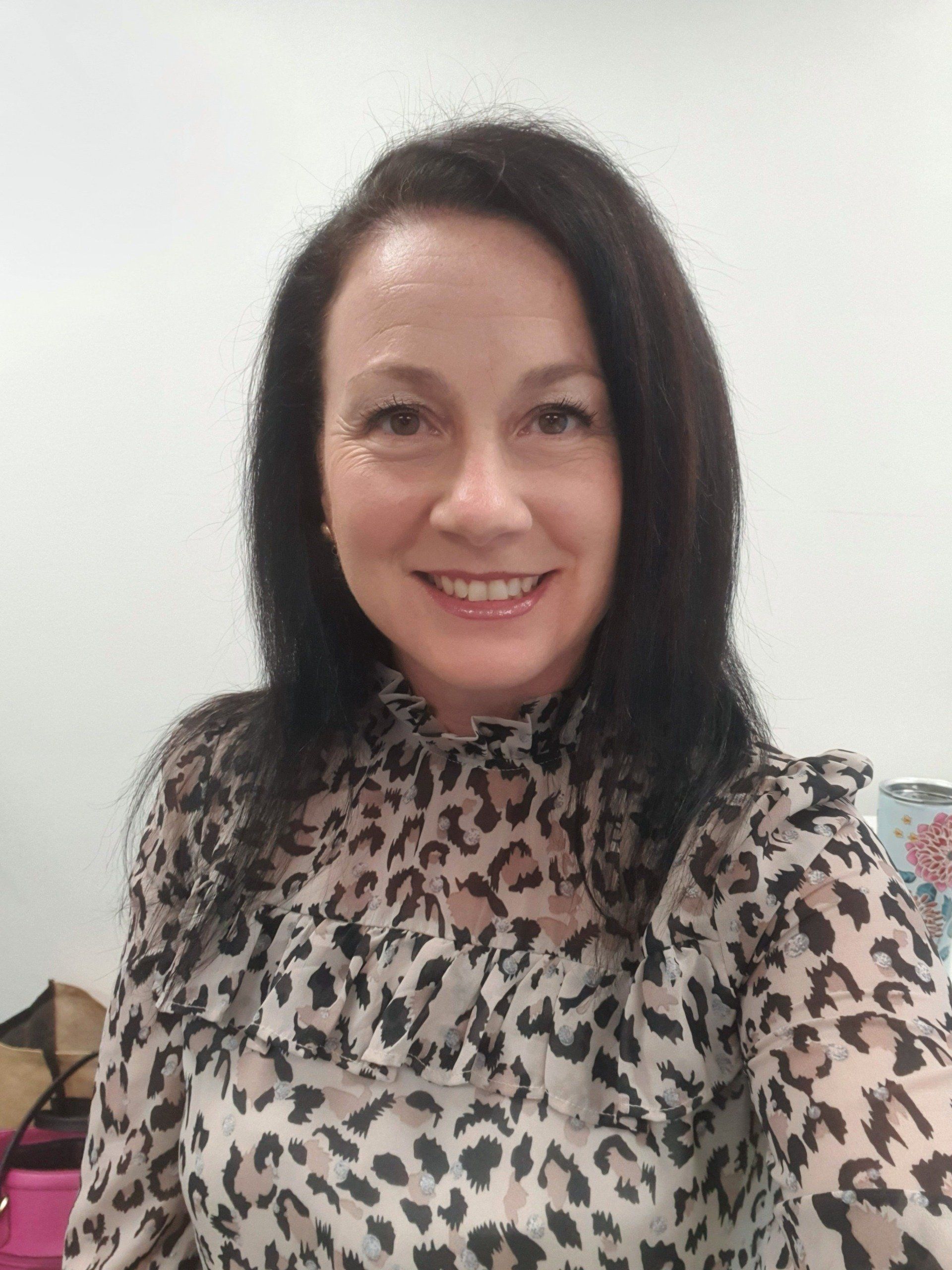 A woman in a leopard print shirt is smiling for the camera.