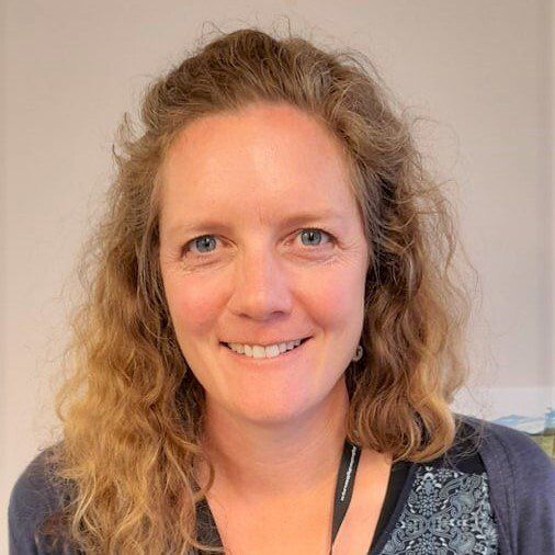 A woman with curly hair is smiling for the camera.