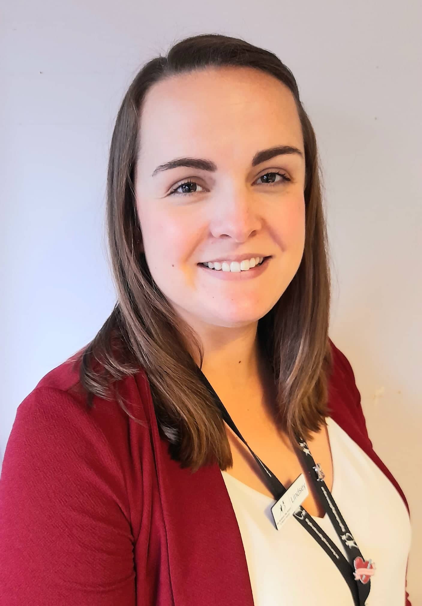 The woman is wearing a lanyard around her neck and smiling for the camera.