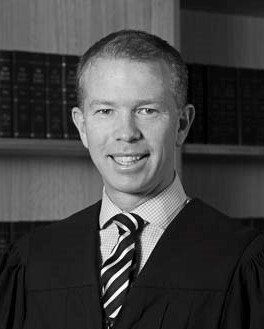 A man in a suit and tie is smiling in a black and white photo.