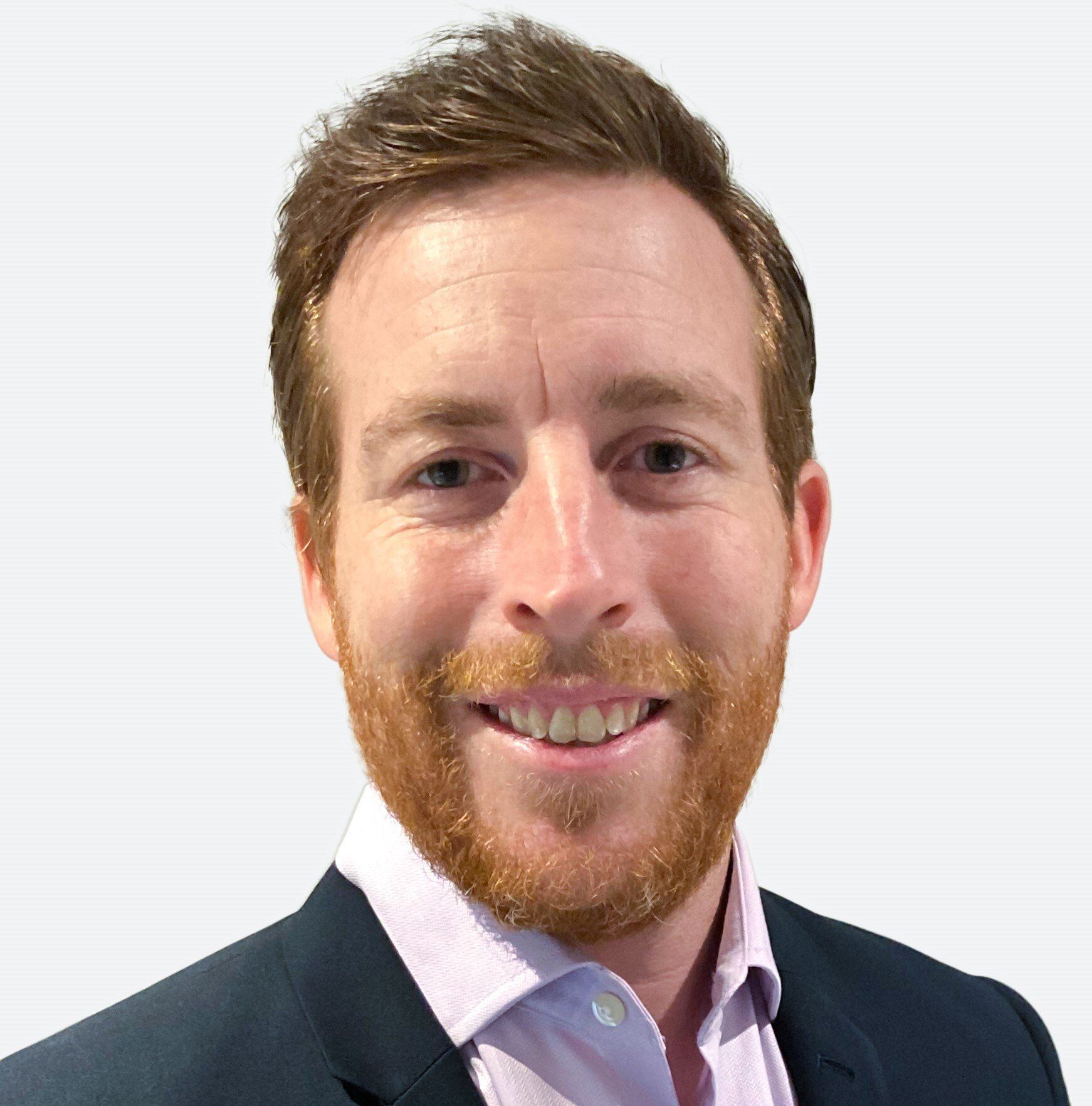 A man with a beard is wearing a suit and smiling.