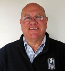 A bald man wearing glasses and a black jacket is smiling for the camera.
