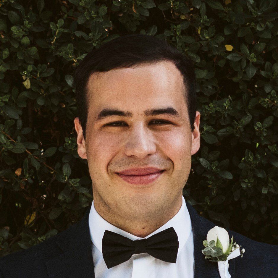 A man in a suit and bow tie is smiling for the camera