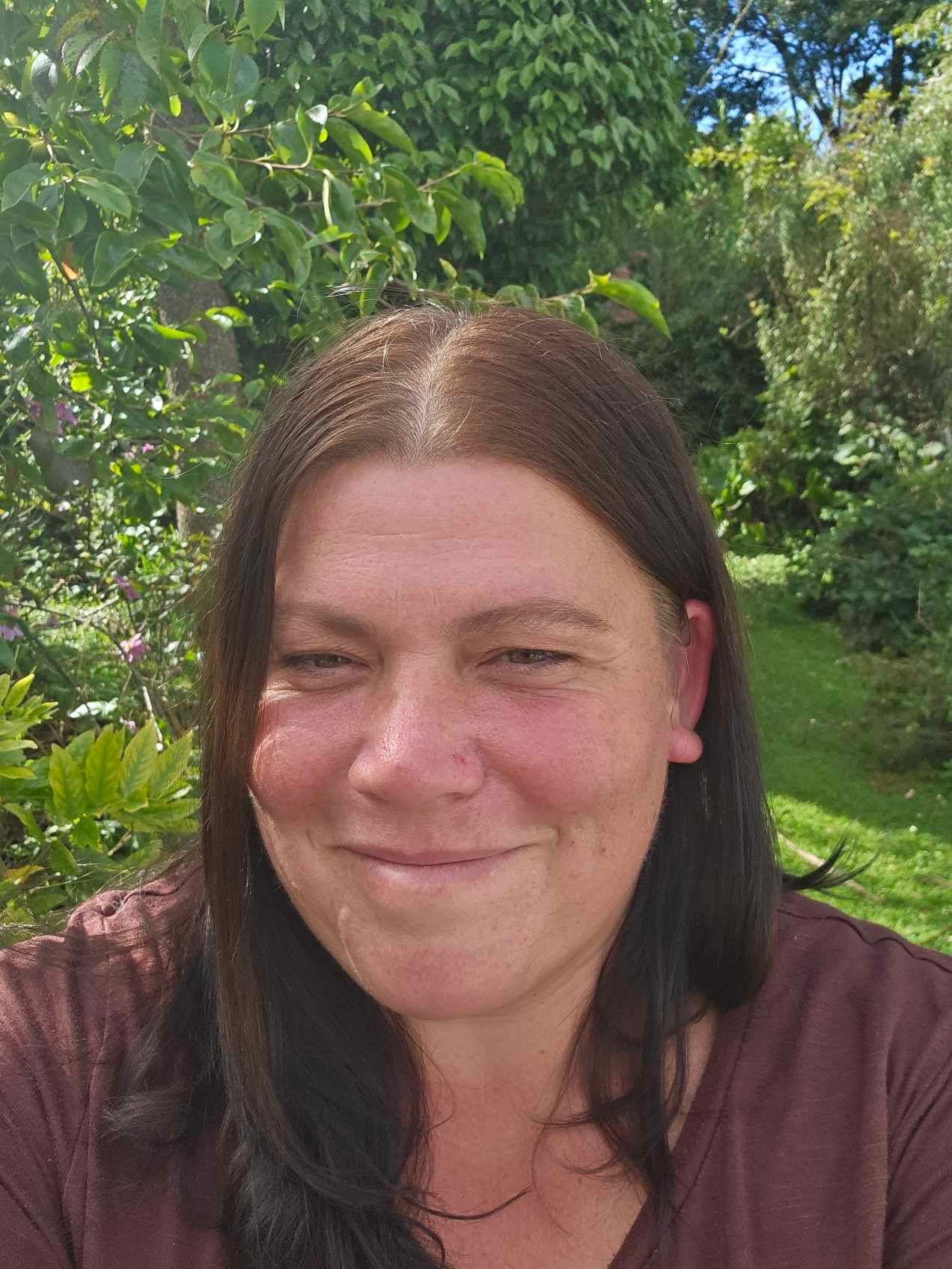 A woman wearing a polka dot shirt is smiling for the camera