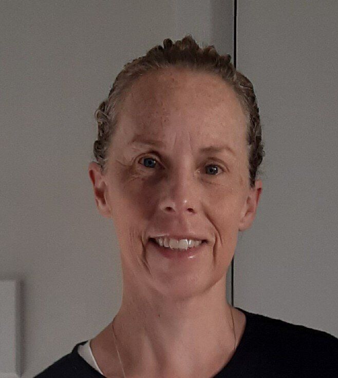 A woman in a black shirt is smiling for the camera.