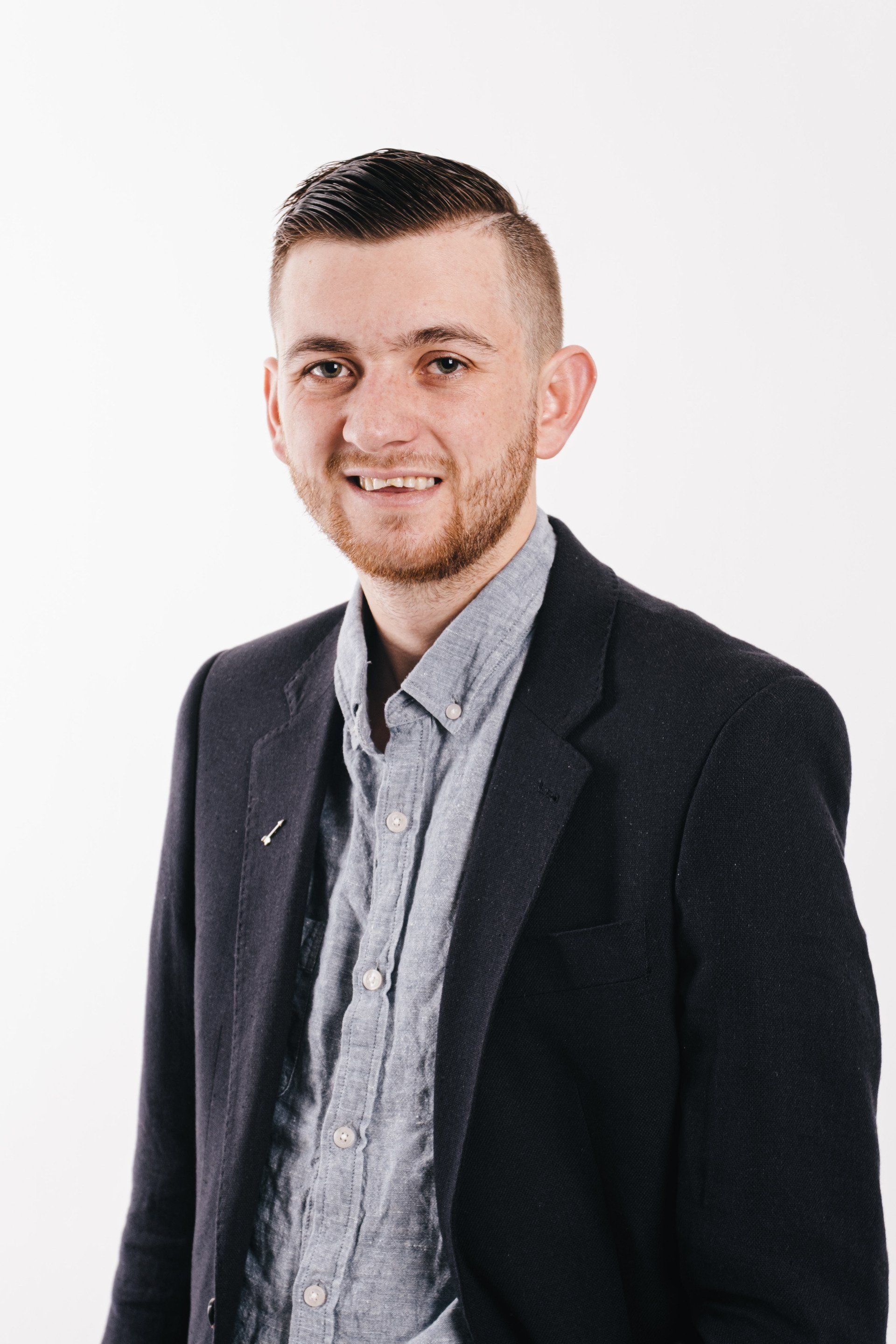 A man with a beard is wearing a suit and smiling.