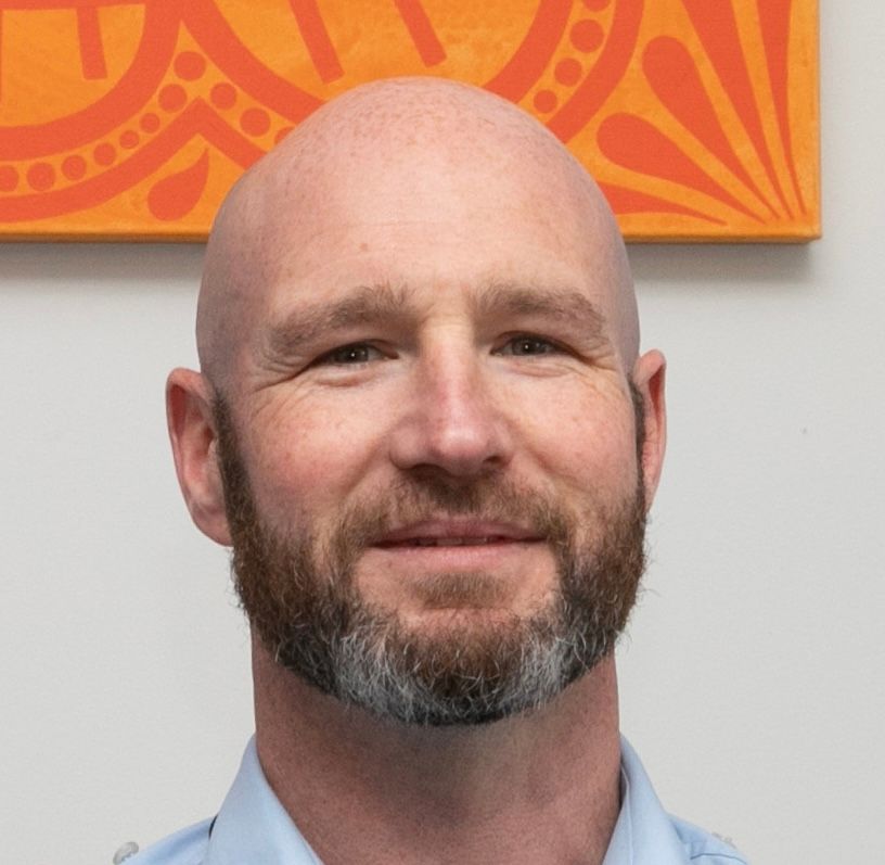 A bald man with a beard is smiling for the camera.