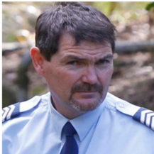 A man with a beard wearing a blue shirt and tie