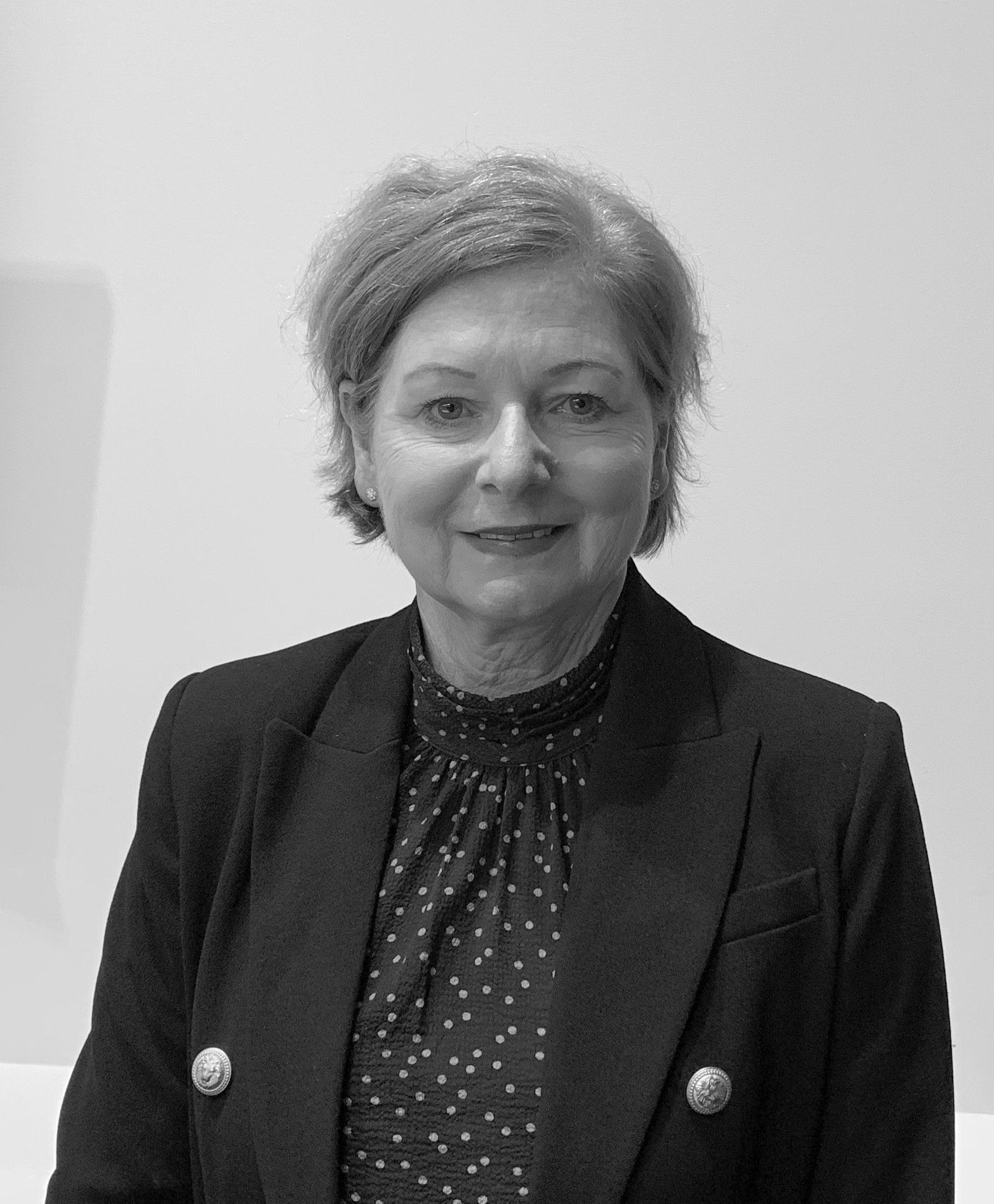 A black and white photo of a woman in a suit and polka dot shirt.