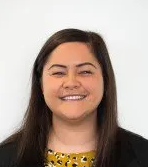 A woman with long hair and a yellow shirt is smiling for the camera.