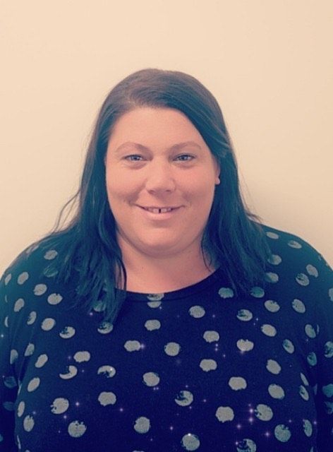 A woman wearing a polka dot shirt is smiling for the camera