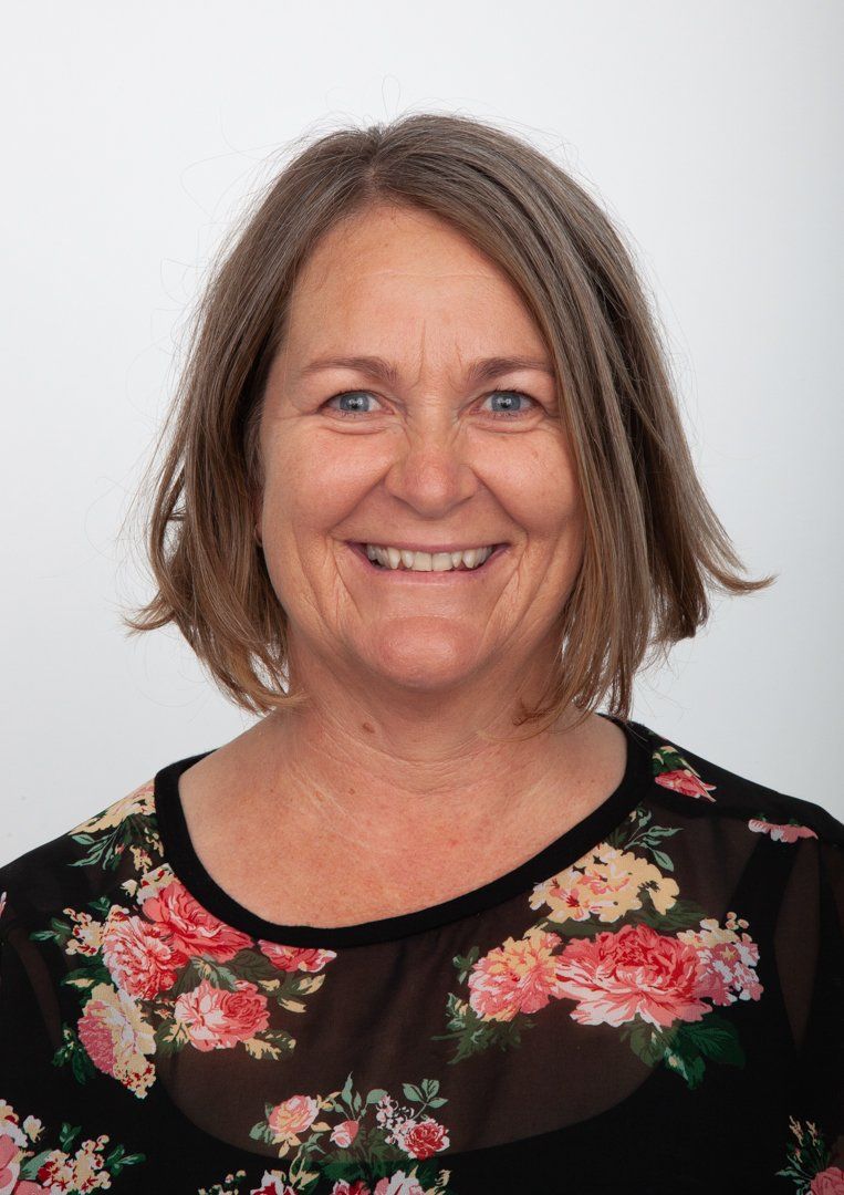 A woman wearing a floral shirt is smiling for the camera.