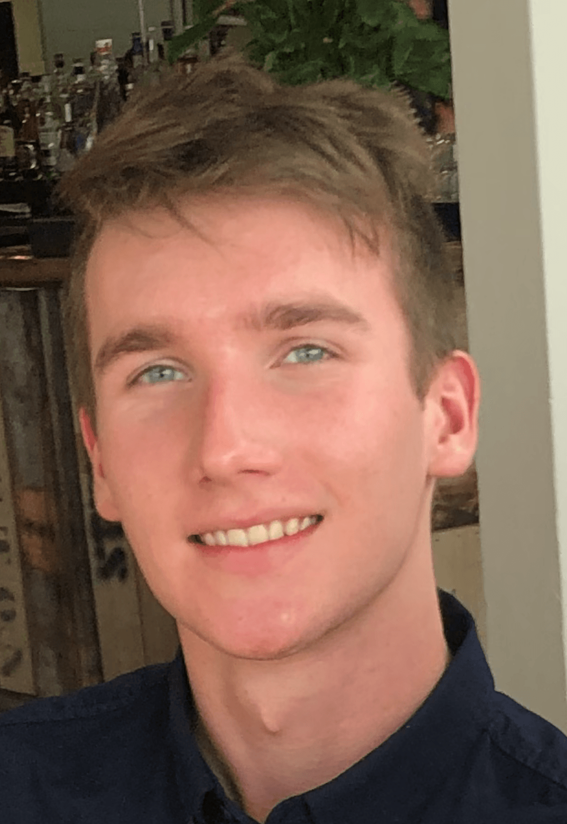 A young man in a blue shirt is smiling for the camera.