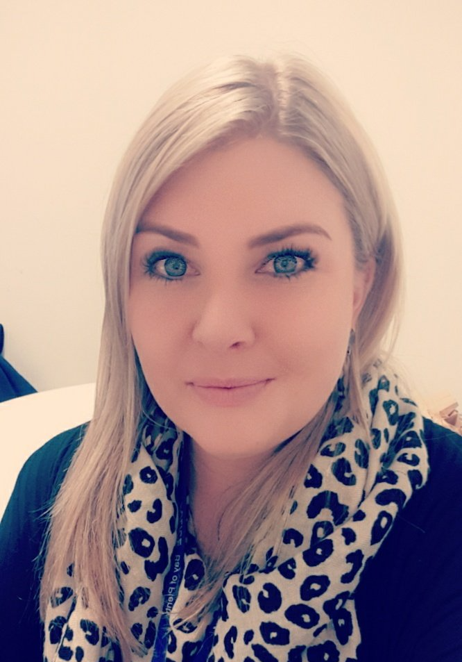 A woman wearing a leopard print scarf is smiling for the camera.