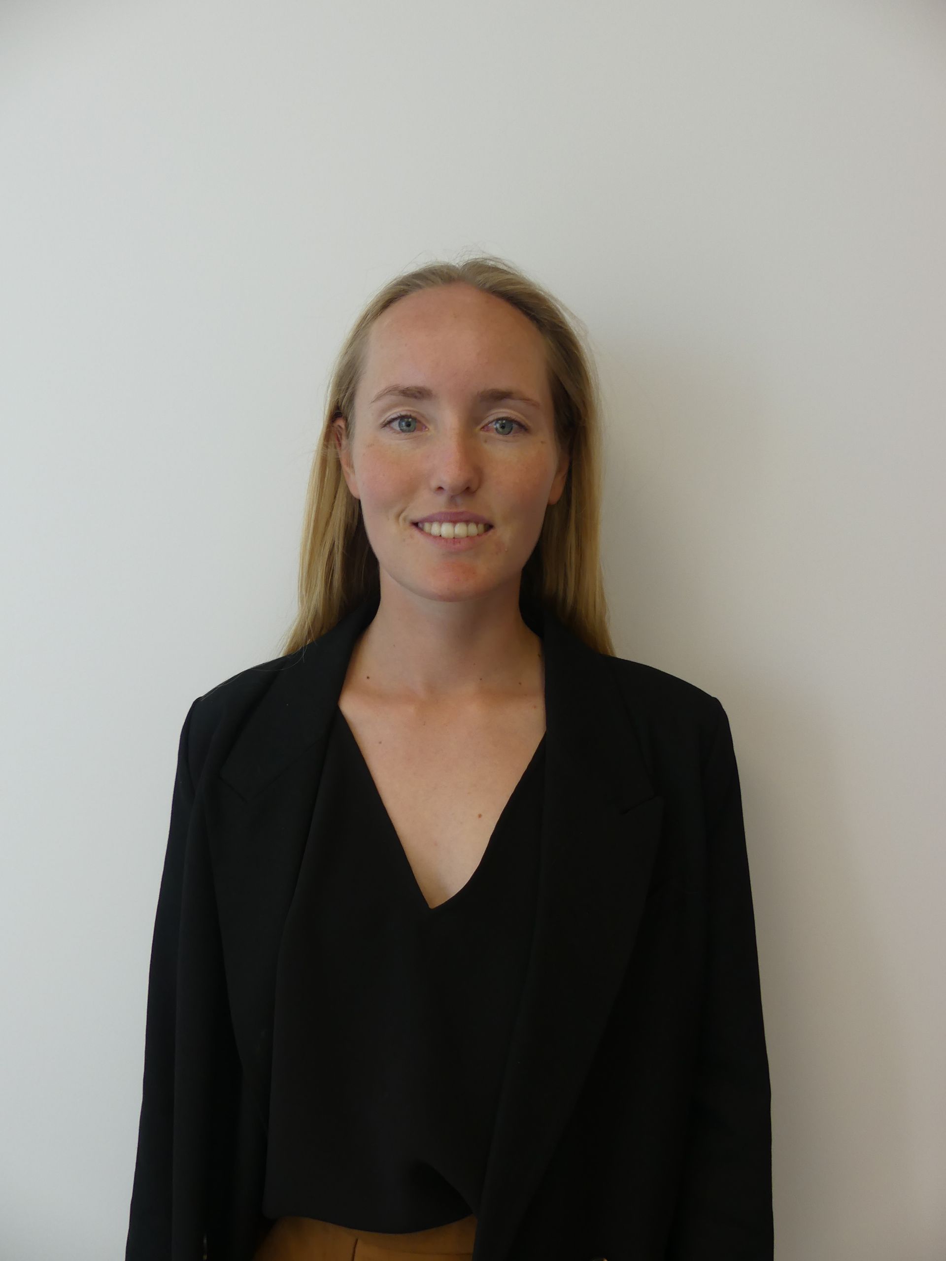 A woman wearing a black jacket and a black shirt smiles for the camera