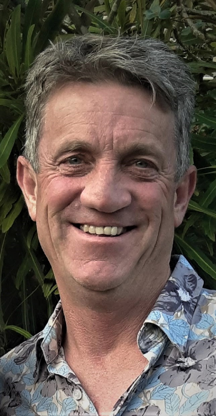 A man in a floral shirt is smiling for the camera.